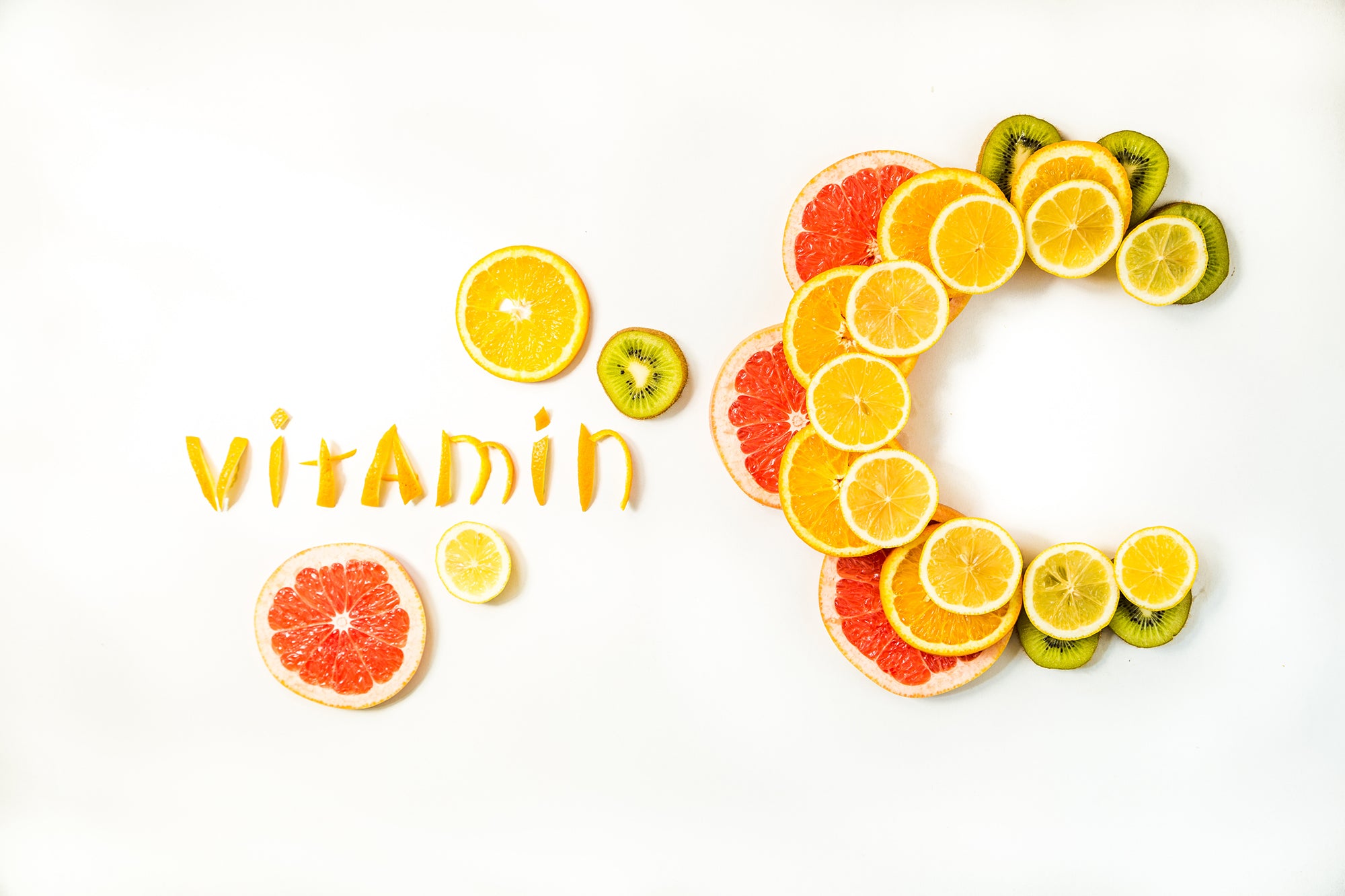 arrangement of citrus fruit slices forming the word Vitamin and a C made of grapefruit, oranges and kiwi