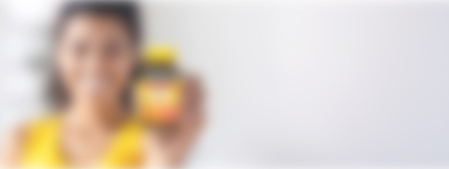 Woman in yellow top holding a Nature Made Vitamin C tablets bottle.