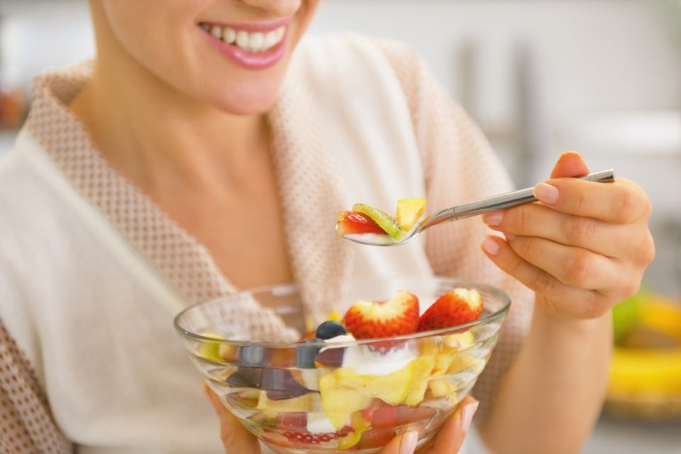 Smiling woman eating a fruit bowl.