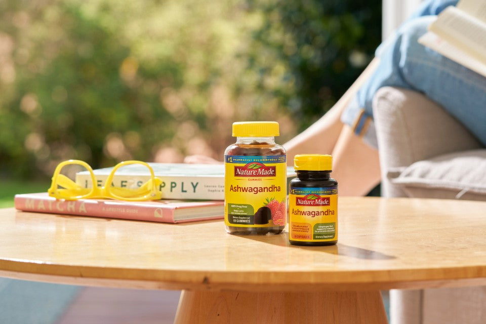 Nature Made Ashwagandha supplements on a wooden table with books and glasses, promoting stress support and wellness.