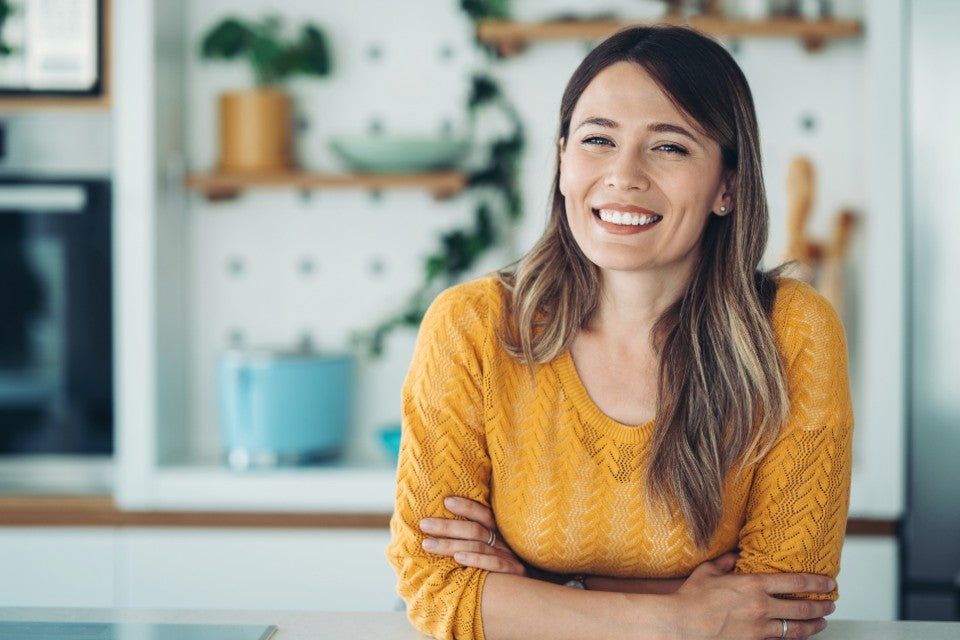 Woman wearing a yellow sweater with a blurred indoor background