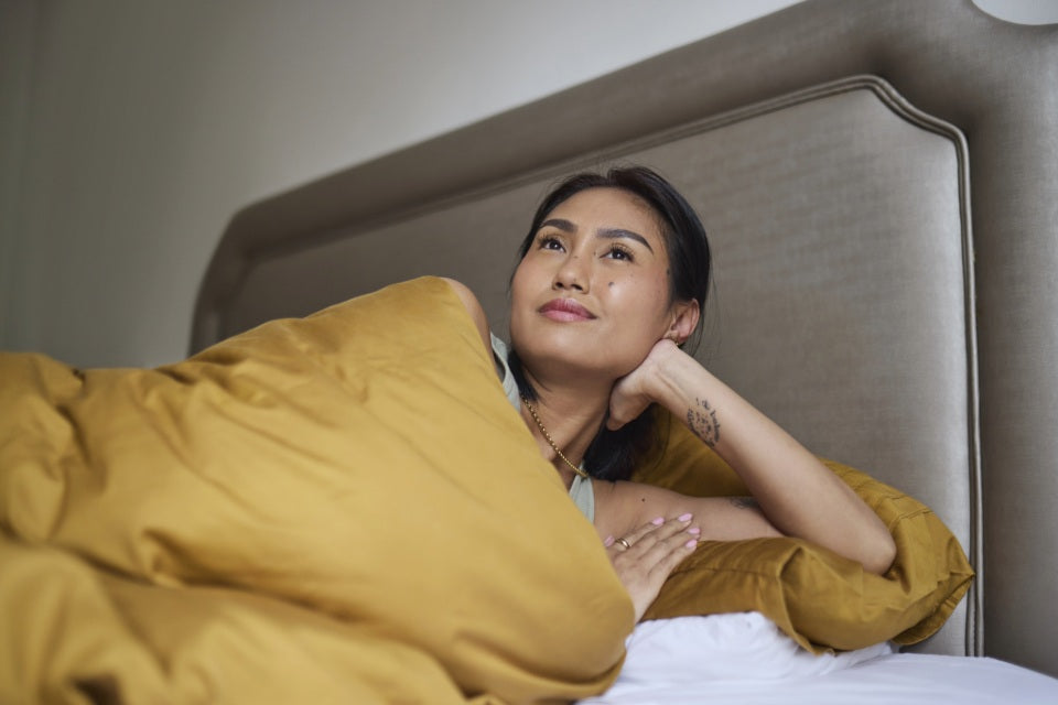 Person resting in bed with yellow bedding.