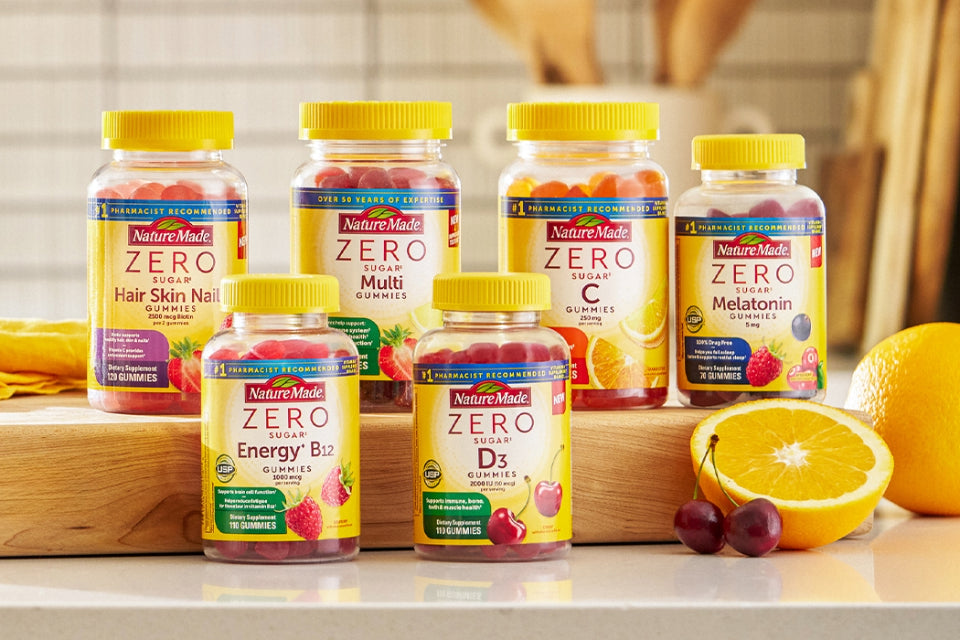 Nature Made Zero Sugar gummies on a counter with slices of oranges and cherries.