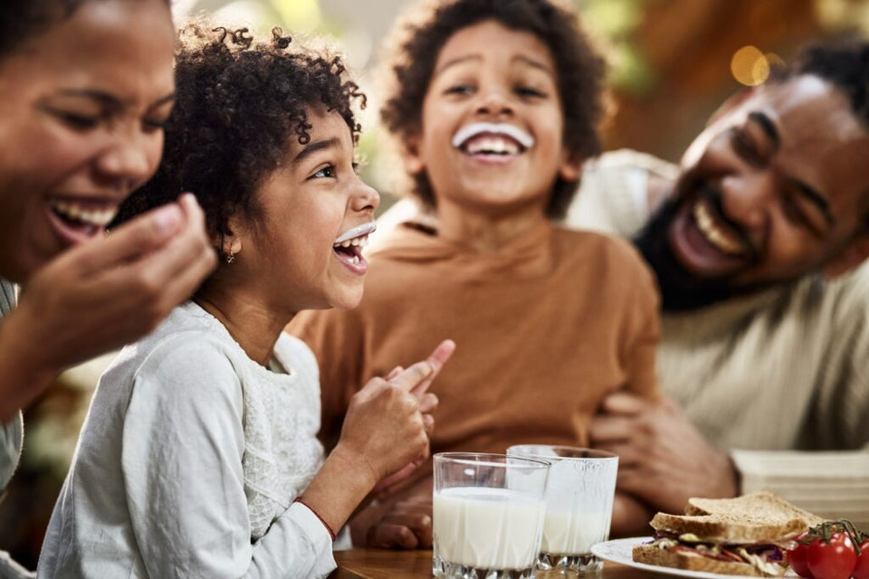 A group of people, 2 adults and 2 kids, gathered around a table, enjoying a meal together.