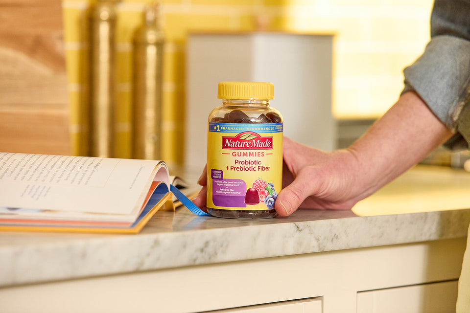bottle of Probiotics + Prebiotic Fiber Gummies on a counter next to a book.