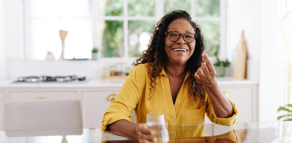 Women taking a vitamin supplement with a glass of water.