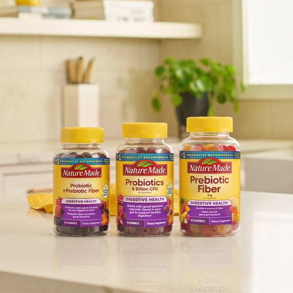 Three NatureMade probiotic supplement bottles on a kitchen counter: Probiotic + Prebiotic Fiber, Probiotics & Bifidus, and Prebiotic Fiber, with a softly blurred kitchen background.